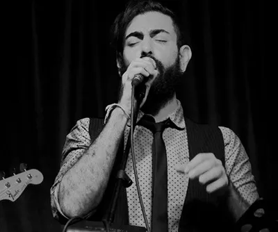 Ferhat Öz zingt in een microfoon op het podium